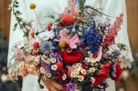 a bright wedding bouquet that includes chamomiles, various pink, red, blue and blush blooms, greenery and billy balls