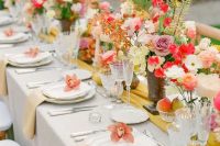 a cheerful wedding tablescape with dusty pink, red, yellow blooms and greenery, pale yellow napkins and a mustard runner
