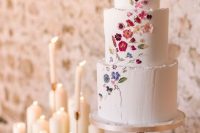 a chic and beautiful white textural wedding cake with edible flowers pressed creating an ombre effect just wows