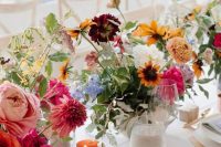 a chic neutral wedding tablescape accented with colorful floral centerpieces and candles, with neutral stationery