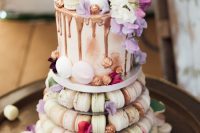 a chic wedding cake with chocolate drip and macarons served under it are all you need for your wedding sweets table