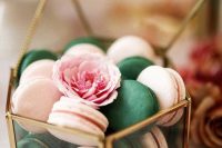 a clear glass box with emerald and pink macarons, with a pink bloom is a chic and lovely way to serve them at the wedding