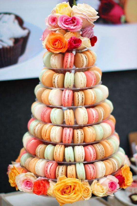 a clear stand with super colorful macarons and with blooms at the bottom and on top the stand is a fantastic alternative to a usual wedding cake