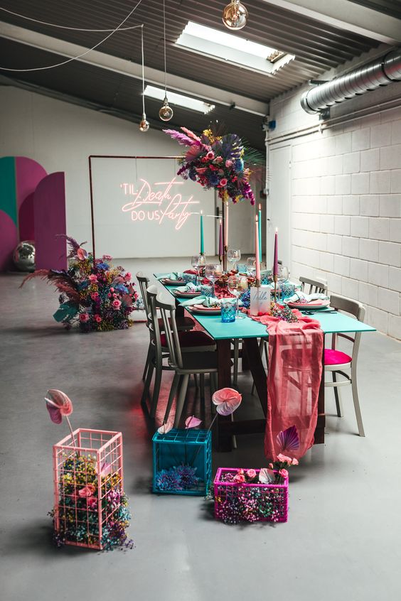 a colorful wedding reception space decorated in hot pink, fuchsia, turquoise, blue, violet, with blooms, cages and candles