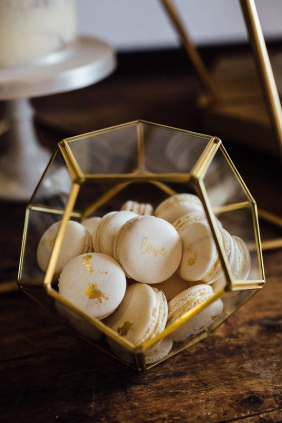 a faceted glass box with gold leaf macarons - this is a simple and cool way to serve them at your wedding