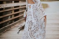 a jaw-dropping boho lace A-line wedding dress wiht a keyhole back on ties, with bell sleeves and a small train for a boho wedding