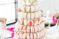 a large macaron tower with bright painted macarons and pink blooms and greenery is a gorgeous idea for a modern colorful wedding
