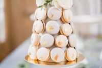 a mini pastel macaron tower of blush macarons with gold leaf and white blooms and greenery is a fantastic idea for a modern wedding