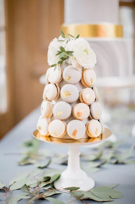 a mini pastel macaron tower of blush macarons with gold leaf and white blooms and greenery is a fantastic idea for a modern wedding