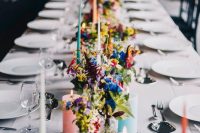 a neutral modern wedding tablescape spruced up with bold blooms and greenery and pastel and colorful candles