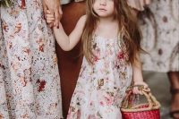 a pink A-line floral dress with a pompom edge, white sneakers and a floral crown plus a pink basket for a summer or spring wedding