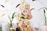 a refined little macaron tower of neutral macarons, pink and white blooms and greenery is a gorgeous idea for a sophisticated wedding