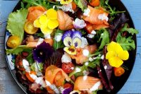 a summer wedding salad of smoked salmon, pansies, tomatoes, arugula, greenery and some yogurt sauce