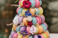 a tower of colorful macarons accented with bright blooms is an amazing alternative to a usual wedding cake