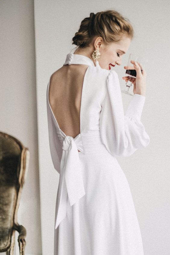 a vintage-inspired plain A-line wedding dress with a keyhole back on buttons and a tie plus long puff sleeves is a chic idea
