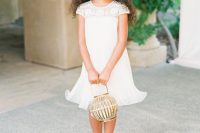a white A-line midi flower girl dress with an embellished neckline, white flats and a greenert crown for a refined look