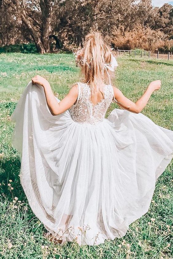 a white flower girl dress with a lace bodice and a plain pleated skirt plus a cutout back for a boho wedding