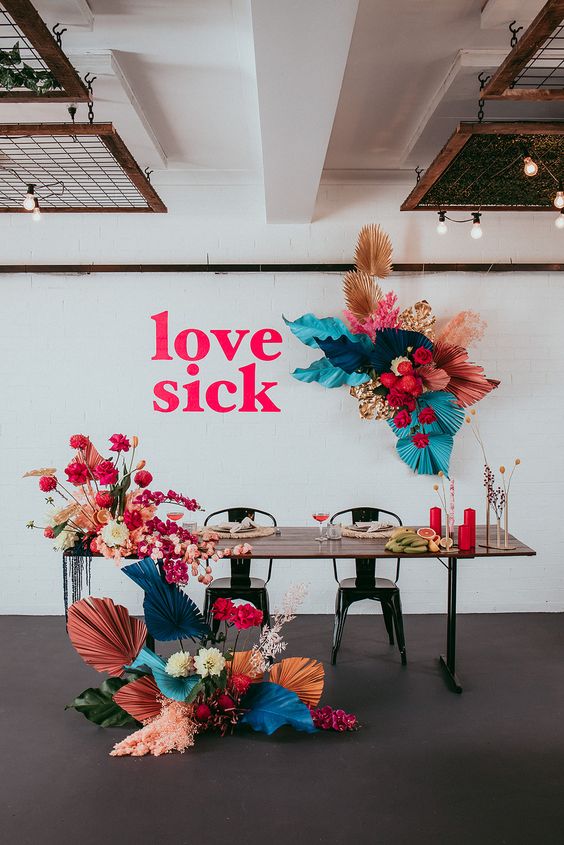 an edgy sweetheart wedding table accented with colorful fronds, blooms and bold candles and letters looks jaw-dropping