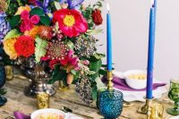 an uncovered wedding table with pops of color – candles, glasses, napkins and bold blooms is a gorgeous idea