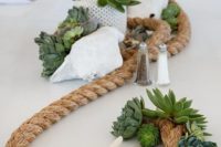 a beachy centerpiece with rope, succulents, starfish, a seashell and potted greenery