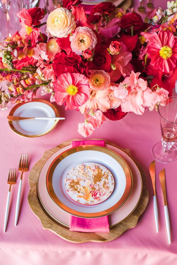 a beautiful and bright pink wedding tablescape with hot pink linens, bright pink and coral blooms and gold cutlery and gold-rimmed plates