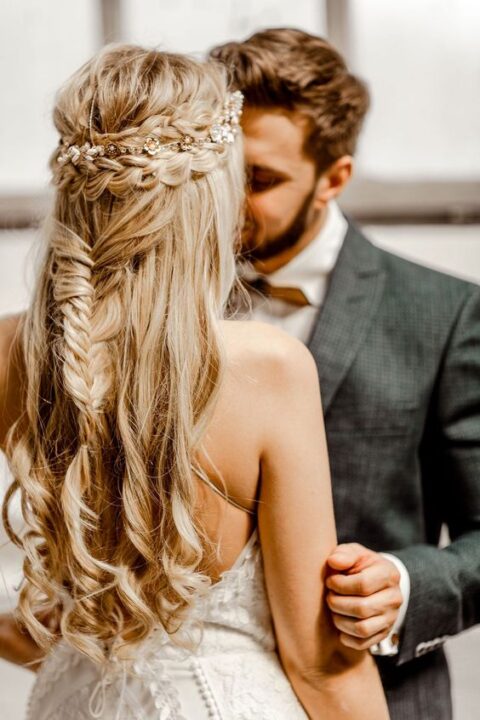 a beautiful boho half updo with a double braided halo, a fishtail braid, waves down and a delicate embellished hair vine
