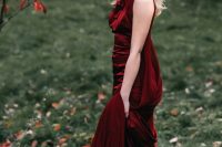 a beautiful burgundy A-line wedding dress with no sleeves, a high neckline and a capelet plus white shoes for a bold and catchy fall wedding