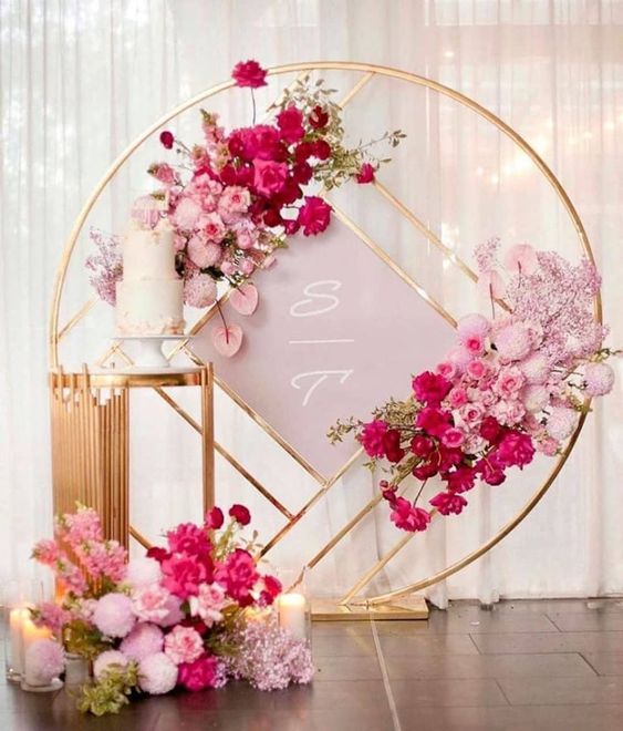 a beautiful ombre pink to fuchsia and gold wedding backdrop with lush florals can be used for a wedding ceremony and not only