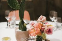 a beautiful wedding centerpiece of potted succulents, blush and peachy blooms and a laser cut table number