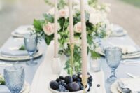 a beautiful wedding table setting with a pale blue tablecloth and glasses, neutral candles and blush blooms is chic