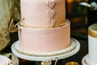 a blush wedding cake decorated with gold glitter and a gold arrow for a Valentine wedding with a soft color scheme