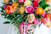a bold wedding bouquet with yellow, orange, pink, blush, yellow blooms, pincushion proteas, greenery and pink pompoms