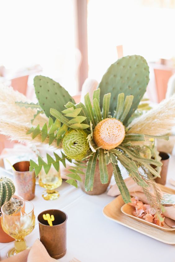 a bold wedding centerpiece of statement blooms, greenery and foliage and large cacti for a desert celebration