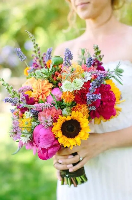 a bright summer wedding bouquet with hot pink peonies, sunflowers, some wildflowers and seed pods is a lovely idea