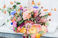 a bright wedding bouquet with hot and tender pink, blue and orange blooms, greenery and bold ribbon is a lovely idea for summer