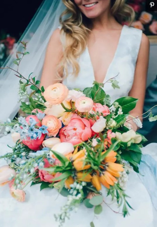 a bright wedding bouquet with pink, orange, yellow, blue and blush blooms, greenery and texture and dimension is amazing for summer