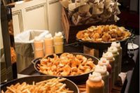 a casual wedding food bar with French fries, nachos and waffles, various dips, sauces and ketchups