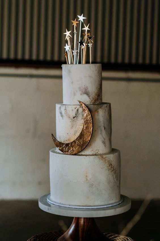 a celestial wedding cake with marble touches and gold glitter, with a moon and some lovely metallic star cake toppers is amazing