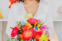 a cheerful wedding bouquet with red, coral, yellow, orange and blue flowers and long colorful ribbons is cool