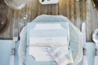 a chic and elegant wedding tablescape with a pale blue tablecloth, charger, menu and elegant cutlery