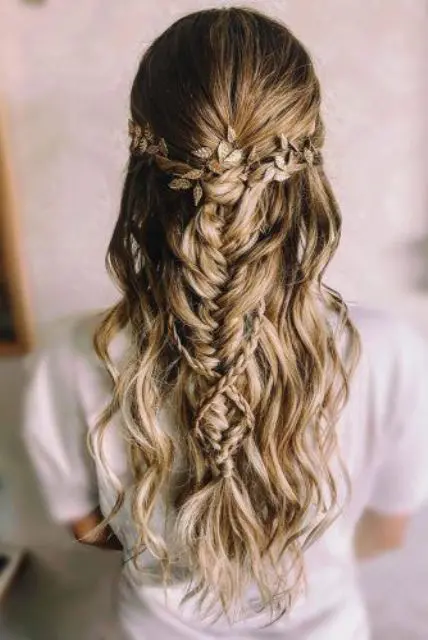 a chic wedding half updo with a large braid, with waves down and a gold leaf hair vine for a boho bride