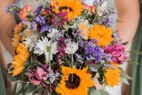a colorful and lovely wedding bouquet of sunflowers, white, pink and purple blooms, greenery and grasses is amazing for a rustic bride
