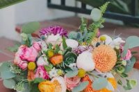 a colorful bouquet with purple, pink, orange and blush blooms and lots of ferns and eucalyptus