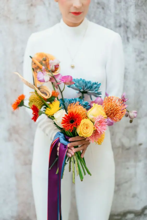 a colorful pop art wedding bouquet with blue, orange, yellow and pink and white blooms and long ribbon is a fun idea for a modern summer wedding