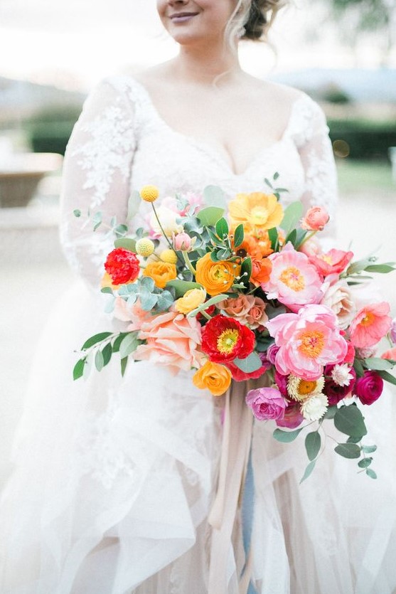 a colorful spring or summer wedding bouquet with marigold, red and pink blooms plus greenery