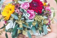 a colorful summer or fall wedding bouquet with pink roses, burgundy dahlias, greenery, dried daisies and sunflowers plus euclayptus