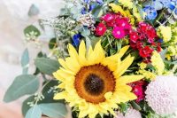 a colorful sunflower wedding bouquet with purple, blue, pink, red and blush blooms, greenery and large sunflowers is amazing for a summer bride