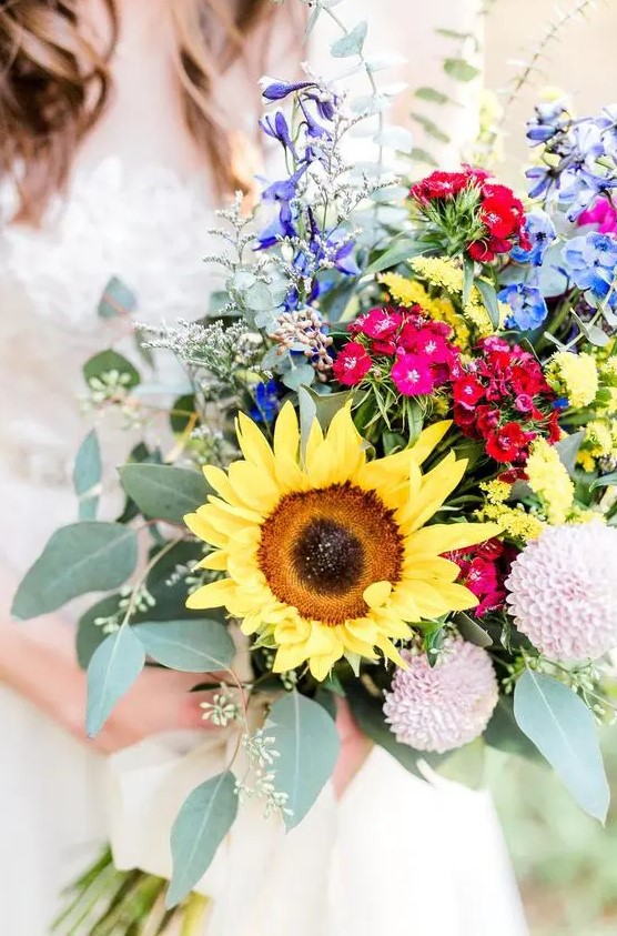 a colorful sunflower wedding bouquet with purple, blue, pink, red and blush blooms, greenery and large sunflowers is amazing for a summer bride