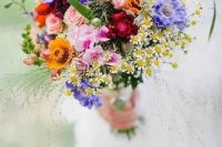 a colorful wildflower wedding bouquet in purple, yellow, pink, fuchsia and with greenery and herbs