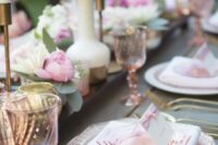 a cool and casual wedding tablescape with pink blooms and plates, pink glasses and gold cutlery, gold candleholders